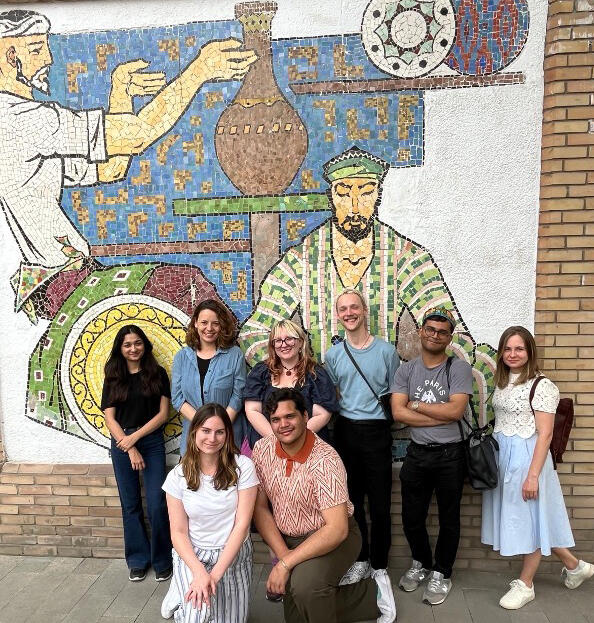 group of students posing in front of a mural